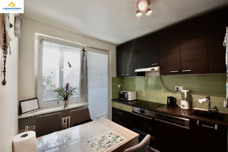 A kitchen in a 3-room apartment with dark furniture, green tiles, and appliances.