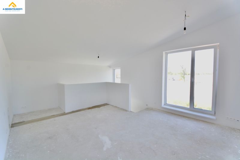 A spacious room in a family house with a large window and a concrete floor.