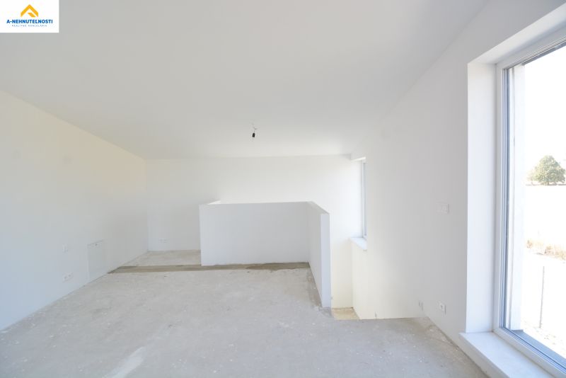 The interior of a family house with an unfinished floor and a large window.