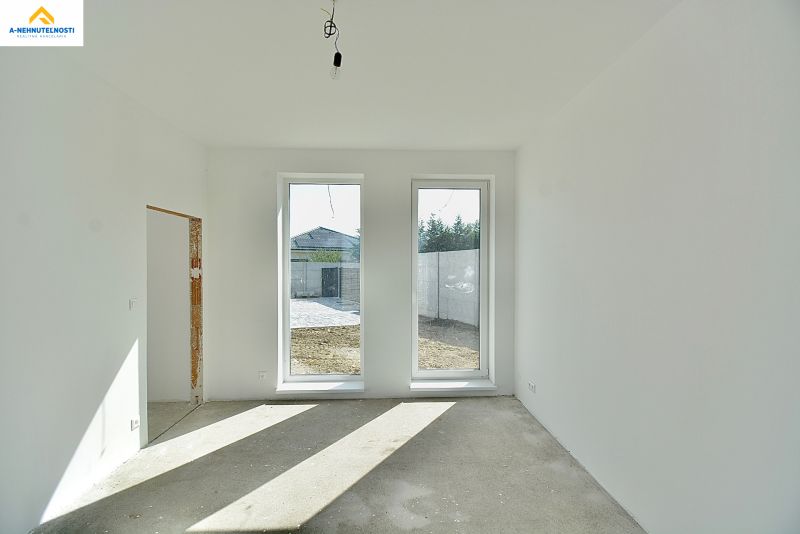 An empty room in a family house with large windows and a view of the garden.