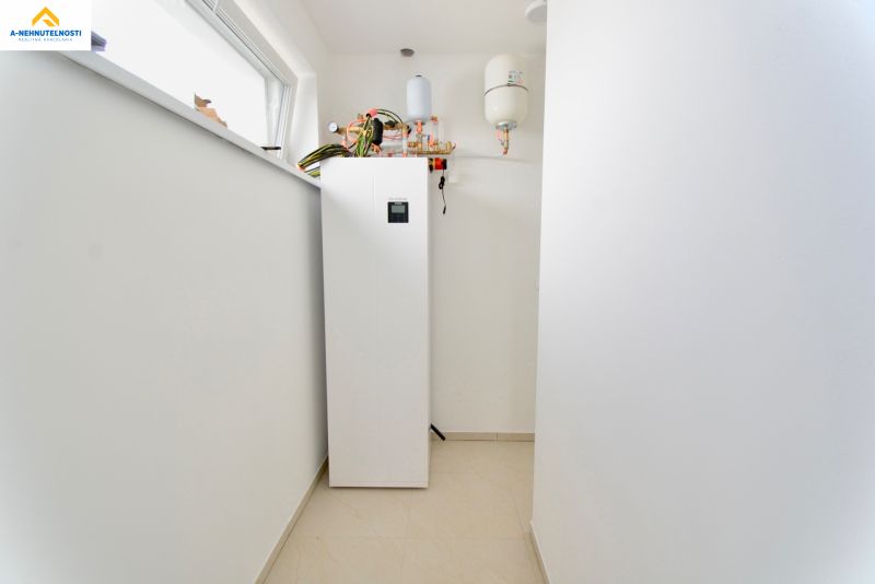 Technical room in a family house with a pump and boiler on white tiles.