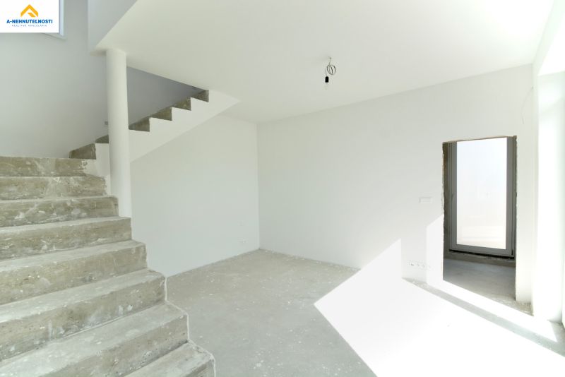 Interior of a family house with a concrete staircase and a large window.