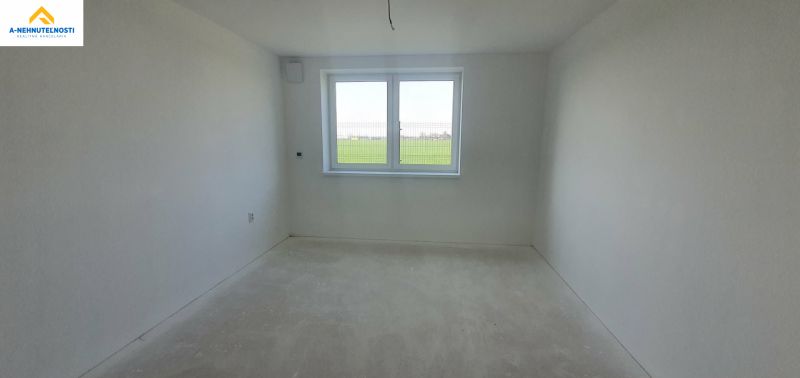 A spacious room in a 3-room apartment with a large window and neutral flooring.