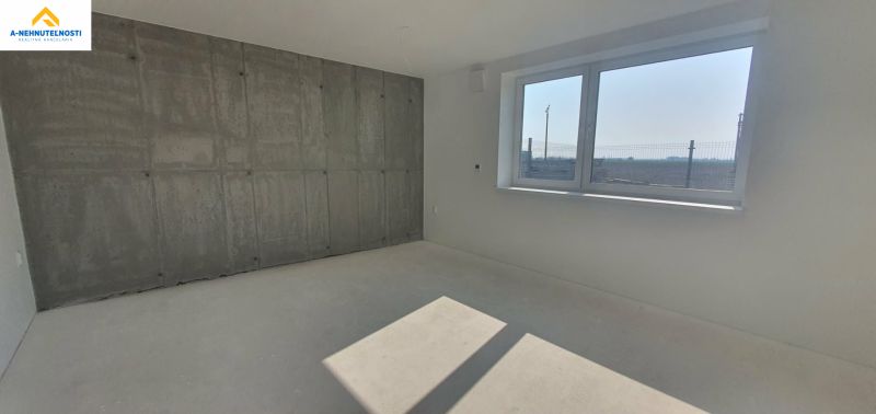 Interior of a 3-room apartment with a concrete wall and a glass window, floor with wooden decor.