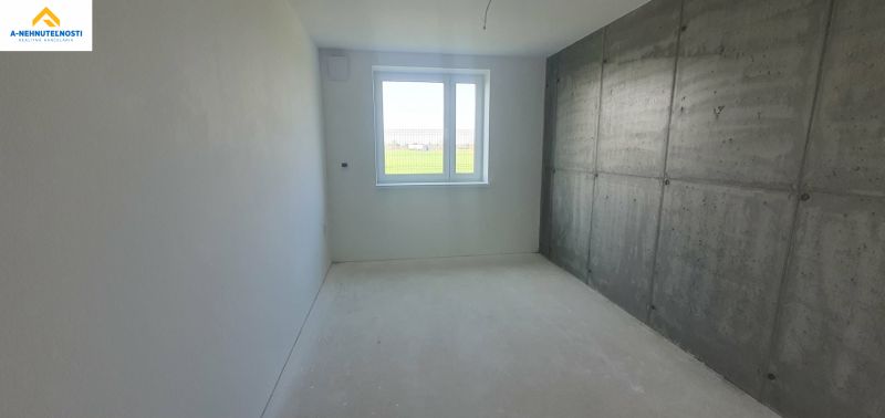 A minimalist room in a 3-room apartment with a concrete wall and white paint.