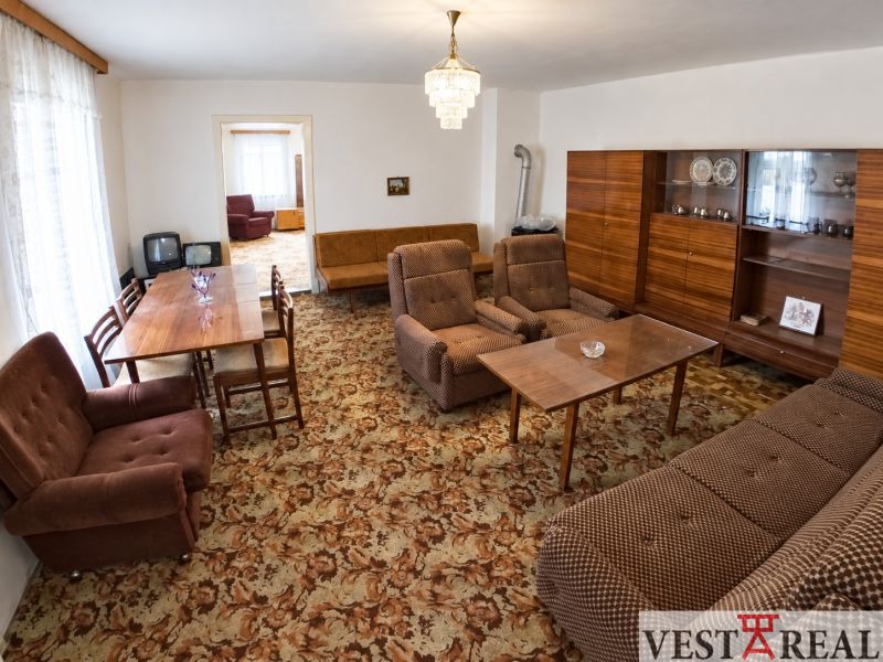 A living room in a family house with typical brown furniture and a patterned carpet.