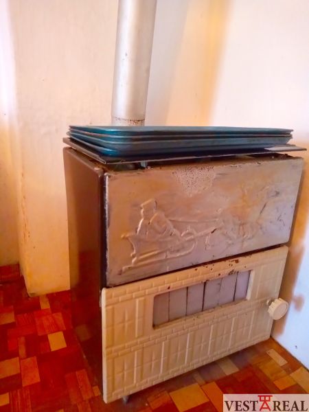 Wood-burning stove with a metal chimney in a family house, floor with a wooden decor.