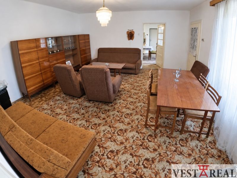 Living room in a family house with carpet pattern, wooden furniture, and a chandelier.