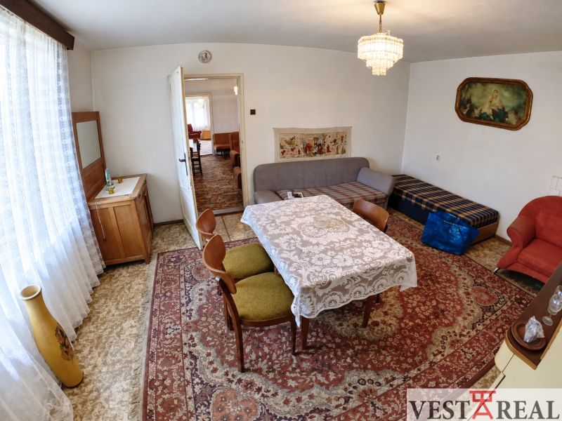 Dining room in a family house with a table, carpet, sofa, and armchairs.