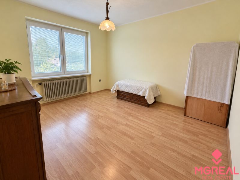 A room with a wooden decor floor in a family house with a bed and antique furniture.