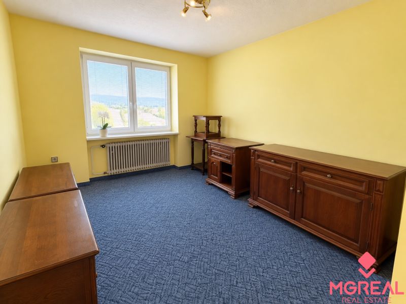 The interior of a family house with wooden furniture, a blue carpet, and yellow walls.