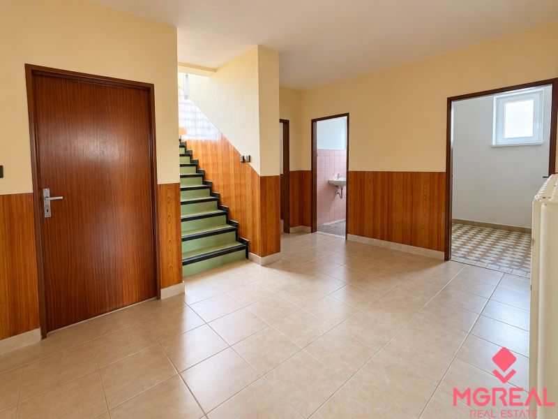 Interior of a family house with tiles, staircase, and wooden wall decor.