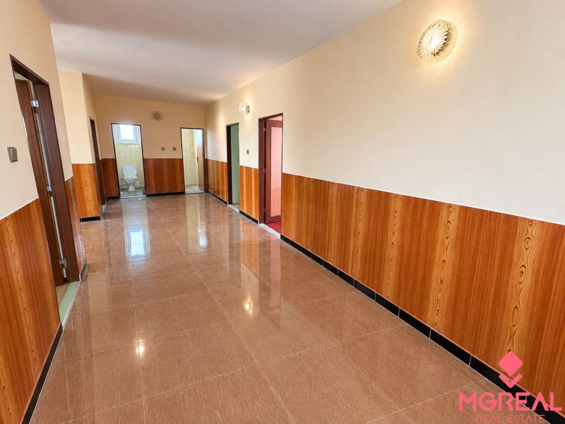A hallway in a family house with tiles and wooden paneling, further is a bathroom.
