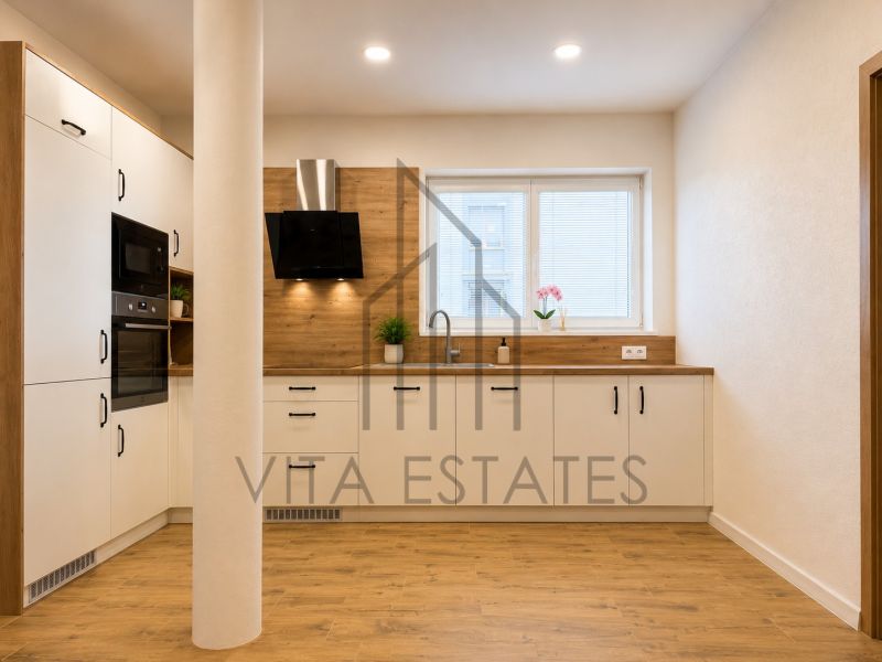 A kitchen of a three-room apartment with a wooden decor floor and built-in appliances.