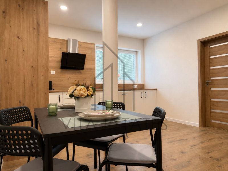 A bright kitchen with a dining table and a wooden decor floor in a 3-room apartment.