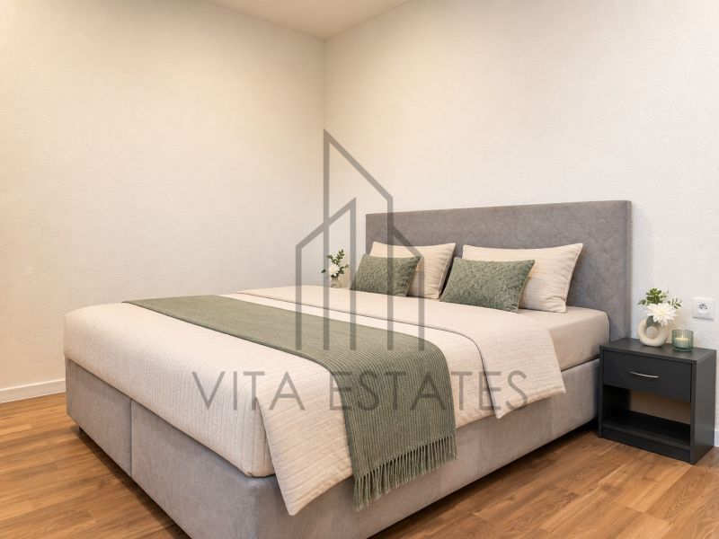 A bedroom with a bed and a wooden decor floor in a three-room apartment.