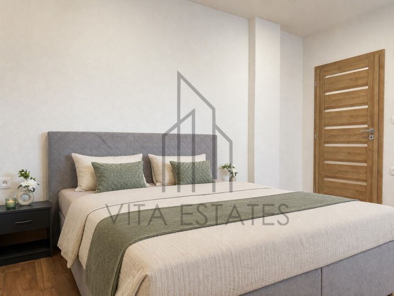 Bedroom with wood-patterned flooring in a 3-room apartment, bed, nightstand, flowers.