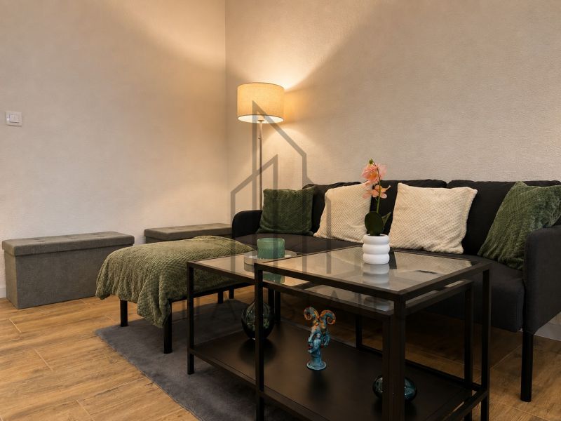 Living room with wood-patterned flooring, a sofa, and a glass table in a 3-room apartment.
