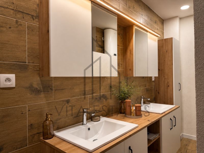 A bathroom with two sinks, wooden decor, a mirror, and storage space in a 3-room apartment.