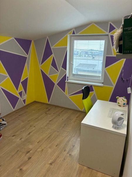 A room in a family house with geometric patterns on the walls and a wooden decor floor.