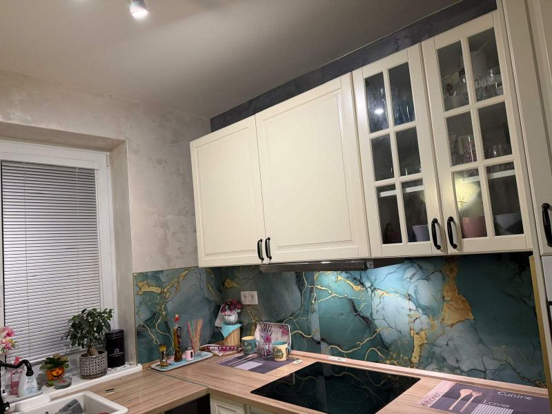 A kitchen with white cabinets and decorative mosaic in a family house.