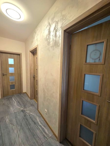 A hallway in a family house with tiled flooring and doors with glass panels.