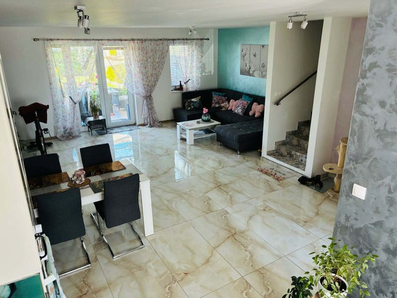 Living room with ceramic flooring, a sofa set, and a dining table in a family house.