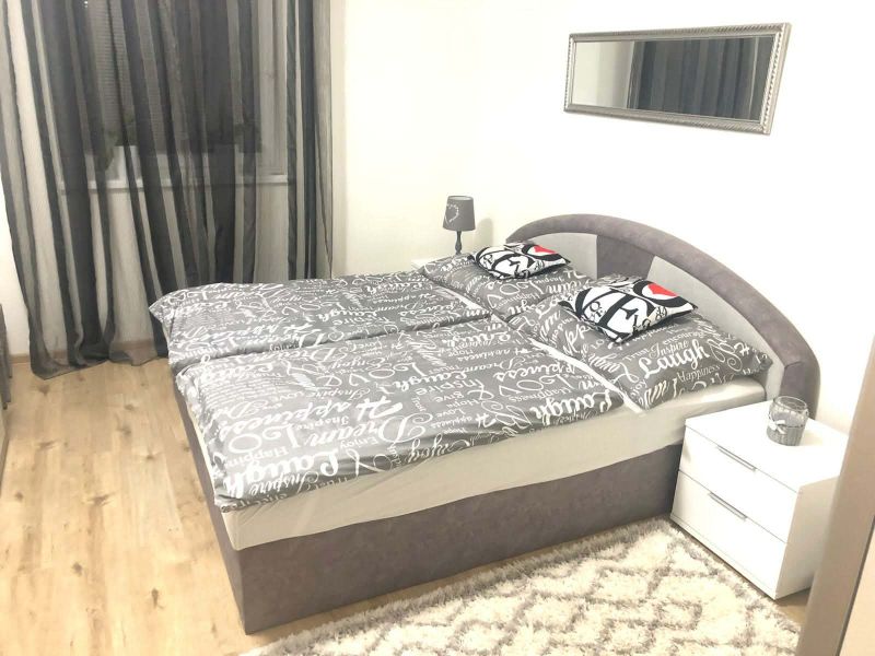 Bedroom in a family house with a gray bed and a floor with a wooden decor.