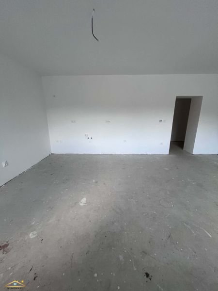 An empty room in a 3-room apartment with a concrete floor and preparation for electrical installation.