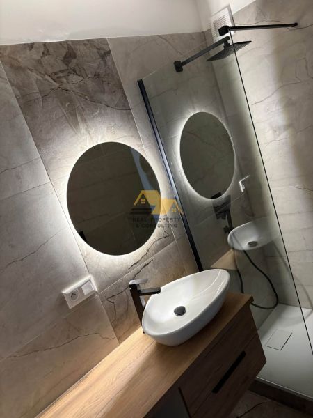 A bathroom in a 2-room apartment with a wooden decorative floor and a modern shower cabin.