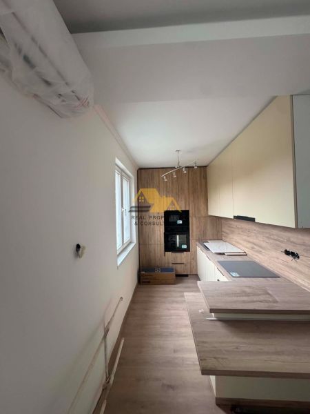 A kitchen in a 2-room apartment with a wood-patterned floor and built-in appliances.
