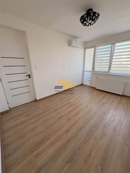 A room in a 2-room apartment with a wooden decor floor and air conditioning.
