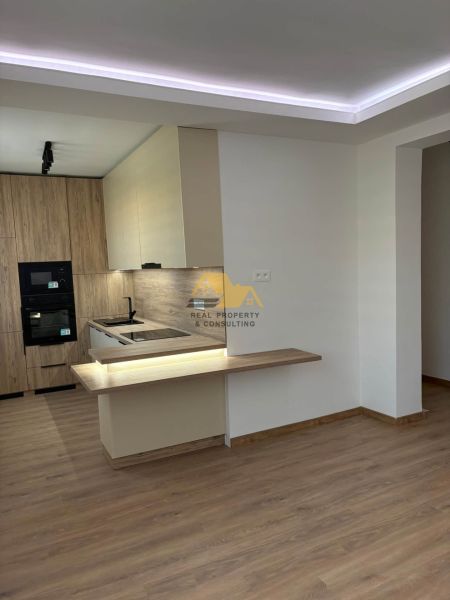 A kitchen with wooden decor and flooring in a 2-room apartment.