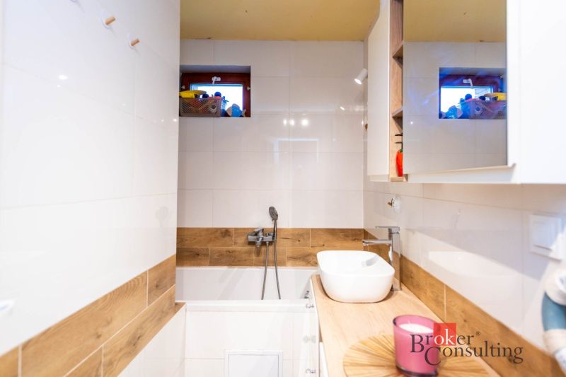 A bathroom in a family house with white tiles and a floor with a wood design.