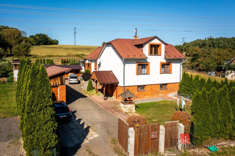 A family house in Potoky with two cars and a gate on a large plot.