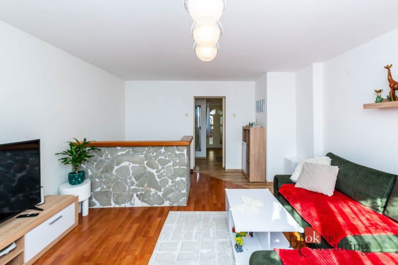 Living room with wood-patterned flooring, a sofa, and a TV in a family house.