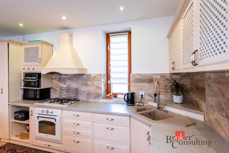 A kitchen in a family house with white cabinets and a tiled wall.
