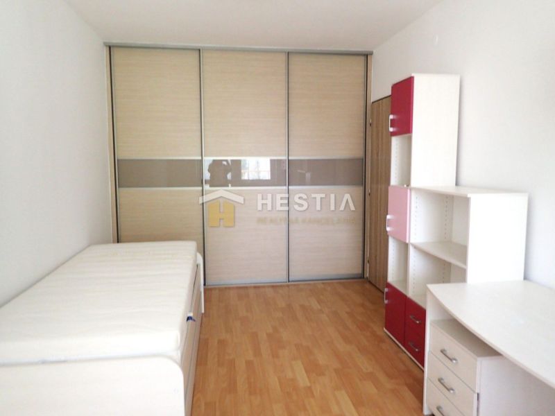 A room in a 3-room apartment with a wooden decor floor, storage space, and a bed.