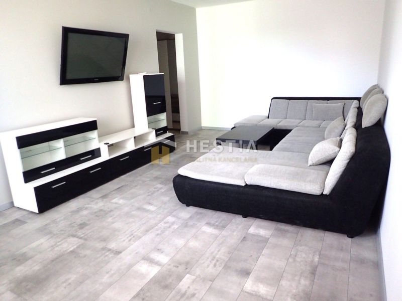 Living room in a 3-room apartment with a gray sofa and a TV on the wall.