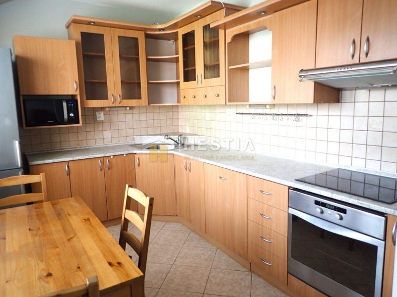 A kitchen in a 3-room apartment, a kitchen unit with a wooden decor, and a dining table.