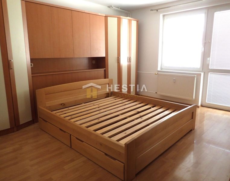 Bedroom in a 3-room apartment with a wooden wardrobe and bed, floor with wooden decor.