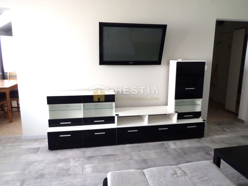 Living room in a three-room apartment with furniture and a TV on the wall.