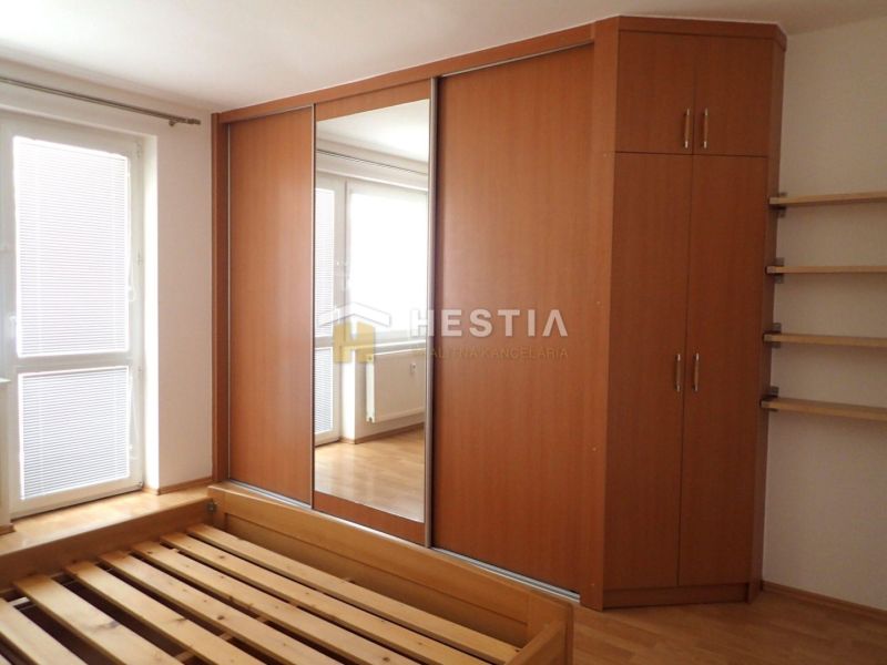 Bedroom in a 3-room apartment with a wardrobe and a bed, floor with wooden decor.