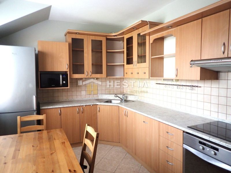 A kitchen in a 3-room apartment with wooden cabinets and a dining table.