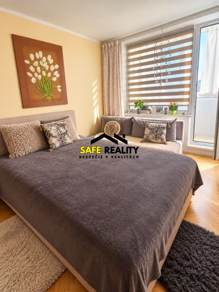 A bedroom in a 3-room apartment with a bed, decorative pillows, and a painting on the wall.