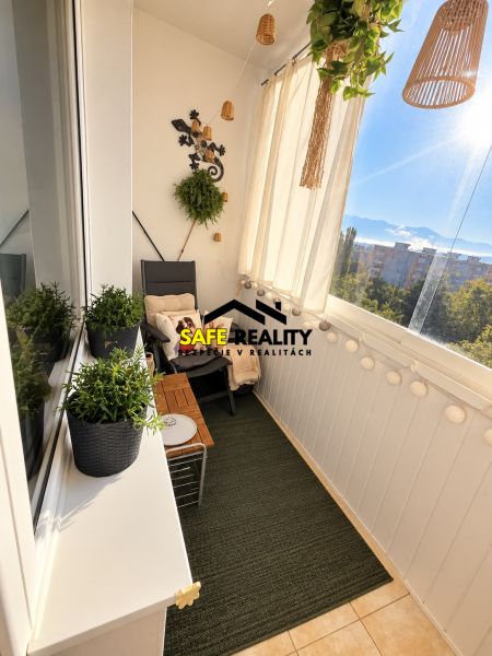 A glazed balcony in a 3-room apartment with plants, a relaxation corner, and a view.