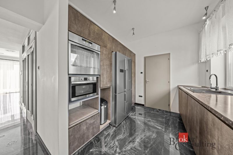 A kitchen in a villa with a marble floor, built-in appliances, and an American refrigerator.