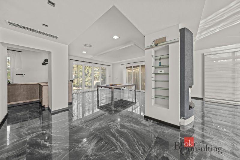 The interior of the villa with glass shelves, marble flooring, and large windows.