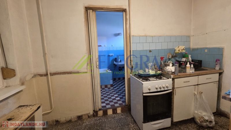 A kitchen with a gas stove and old equipment in a family house with blue tiles.