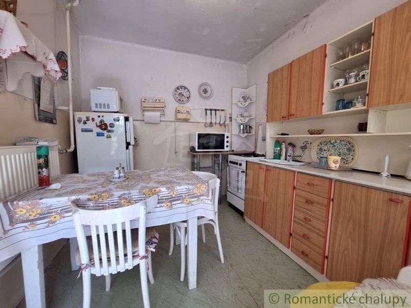In the kitchen of the family house, there is a table with chairs and a kitchen unit.